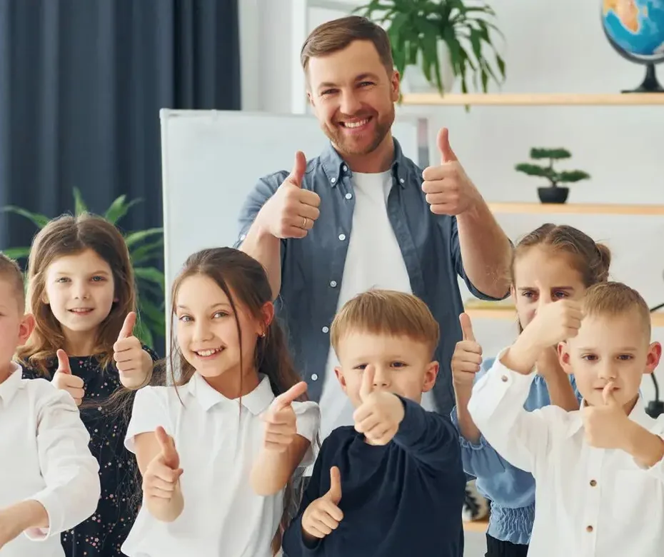 Showing thumbs up. Group of children students in class at school with teacher
